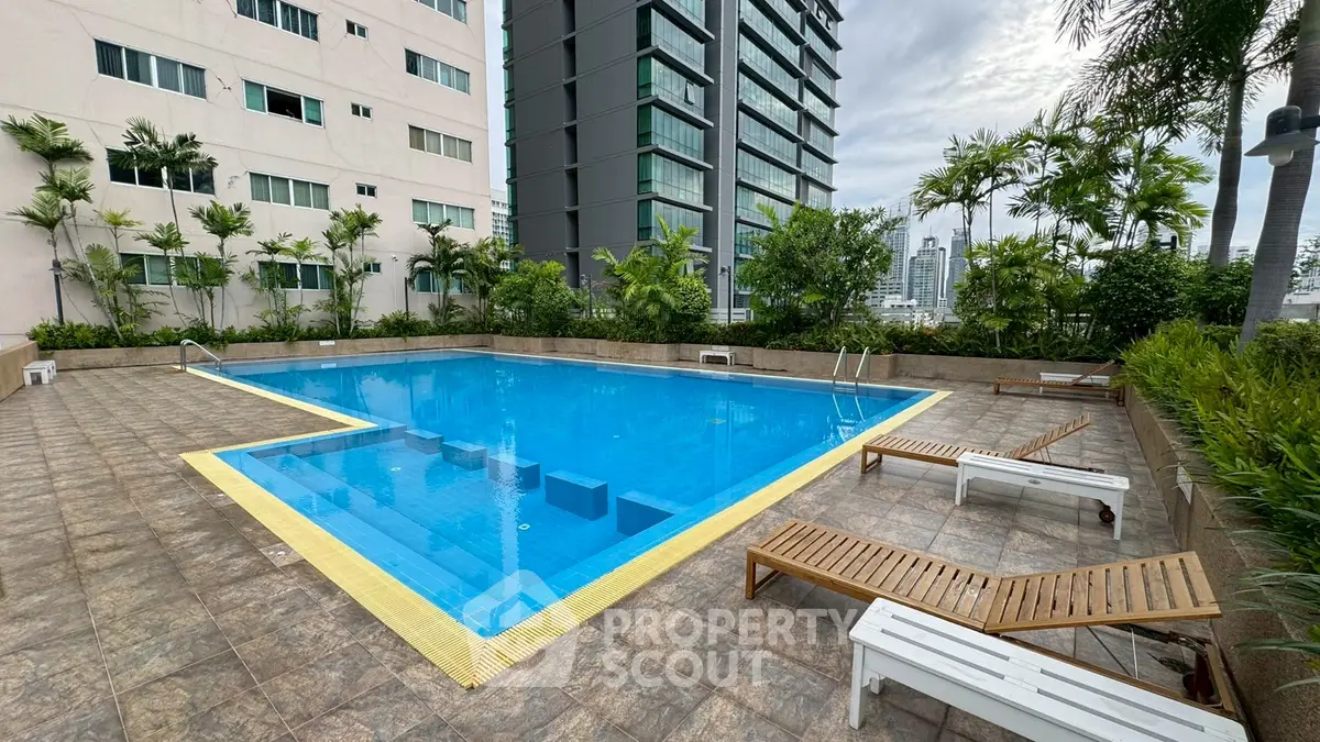 Luxurious rooftop pool with city views and lounging area in modern residential complex.