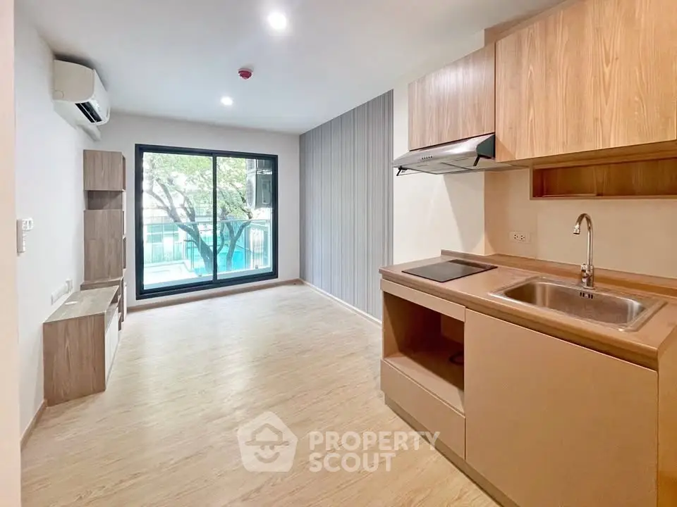 Modern open-plan living room with sleek kitchen and large window view.