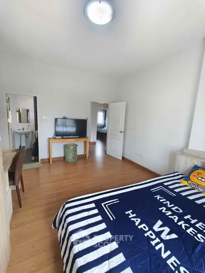 Spacious bedroom with modern decor and wooden flooring, featuring a cozy bed and a TV setup.