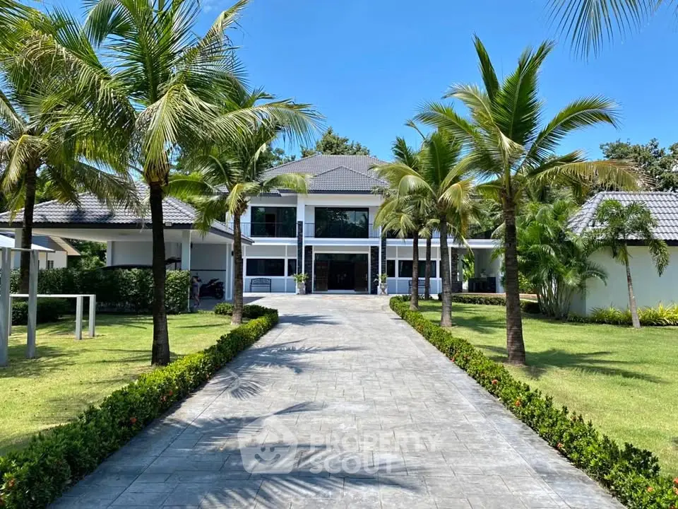 Luxurious tropical villa with palm-lined driveway and manicured garden