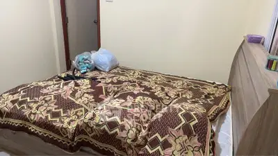 Cozy bedroom with floral bedspread and wooden dresser, ideal for a comfortable living space.