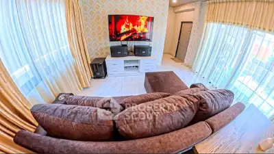 Luxurious living room with plush sofa and large TV, featuring elegant curtains and modern decor.