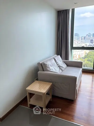 Cozy living room with city view, featuring a comfortable sofa and wooden side table, perfect for relaxation.