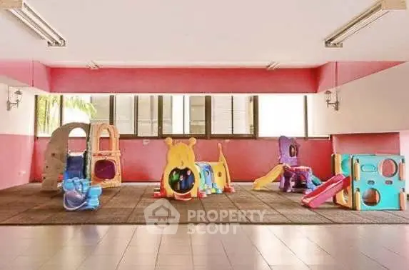 Spacious indoor play area with colorful playground equipment in a residential building.