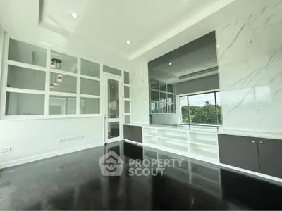 Spacious modern living room with sleek dark flooring and large windows offering natural light.