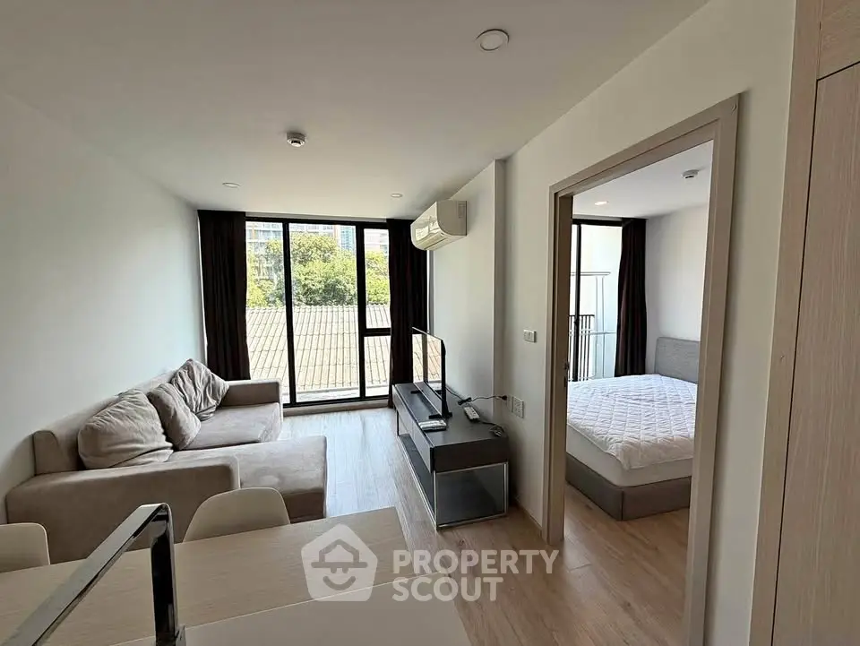 Modern apartment interior with cozy living room and bedroom, featuring large windows and natural light.
