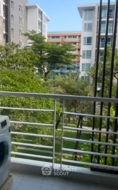 Charming balcony view with lush greenery and modern apartment buildings.