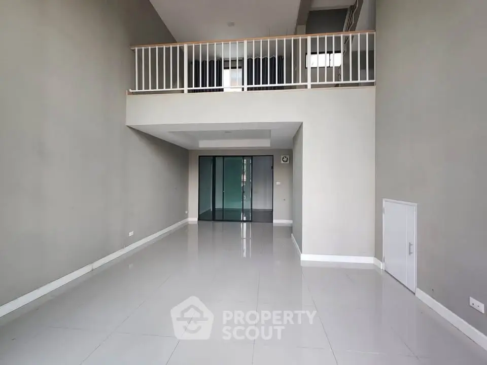 Spacious modern living room with high ceiling and mezzanine, perfect for stylish urban living.