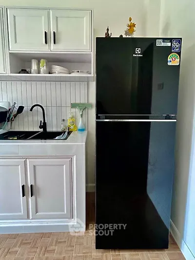 Modern kitchen with sleek black fridge and white cabinetry