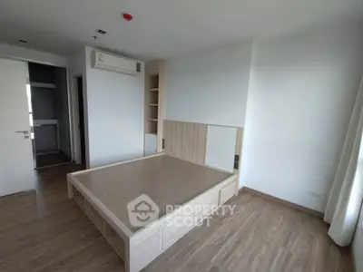 Spacious bedroom with modern wooden flooring and built-in storage in a minimalist apartment.