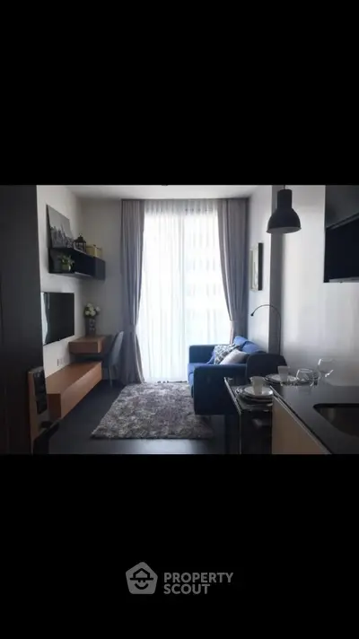 Modern living room with cozy sofa and natural light from large window.