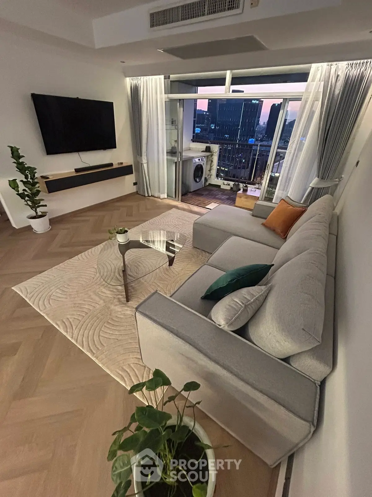 Modern living room with balcony view, featuring sleek furniture and stylish decor in a high-rise apartment.