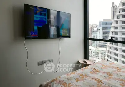 Modern bedroom with city view and wall-mounted TV in urban apartment