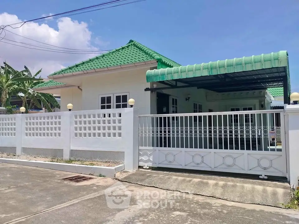 Charming single-story home with green roof and gated driveway in a serene neighborhood.