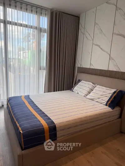 Modern bedroom with stylish decor and large window offering natural light.