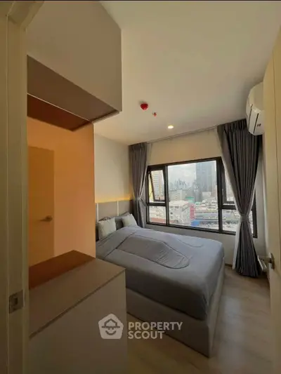 Modern bedroom with city view, featuring large windows and stylish decor in a high-rise apartment.