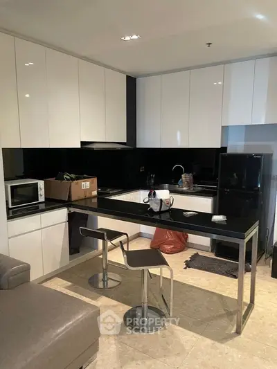 Modern kitchen with sleek black countertops and white cabinets, featuring a stylish breakfast bar and contemporary stools.
