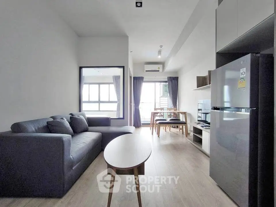 Modern living room with sleek furniture and natural light, featuring a cozy sofa and stylish dining area.