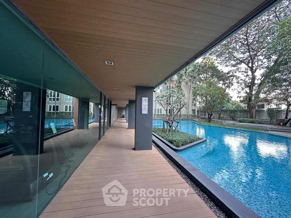 Luxurious modern apartment complex with stunning poolside view and elegant wooden deck.
