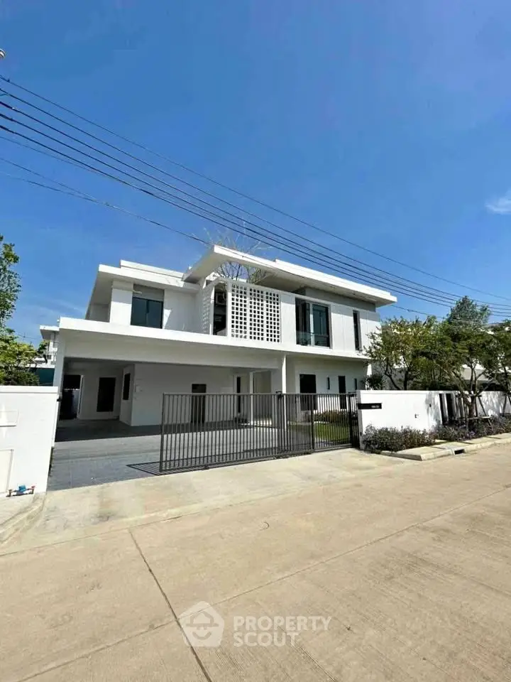 Stunning modern white two-story house with spacious driveway and lush greenery.