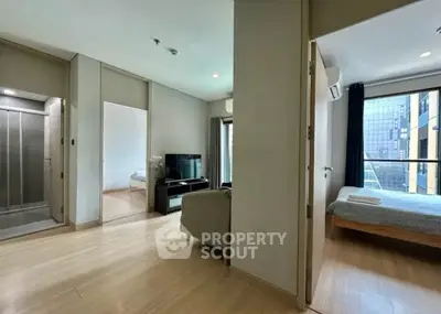 Modern apartment interior with spacious living room and bedroom, featuring large windows and wooden flooring.