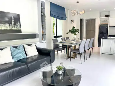 Modern living room with sleek black sofa, elegant dining area, and contemporary decor.