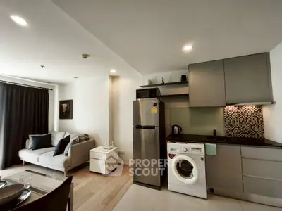 Modern open-layout kitchen with stainless steel appliances and cozy living area.