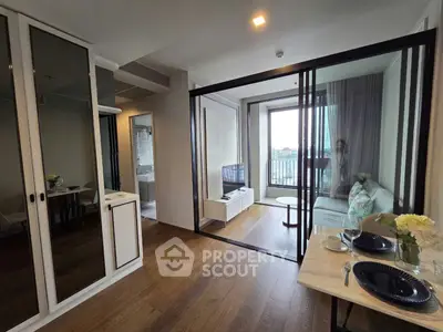 Modern living room with glass partition and balcony view, featuring elegant dining setup and cozy seating area.