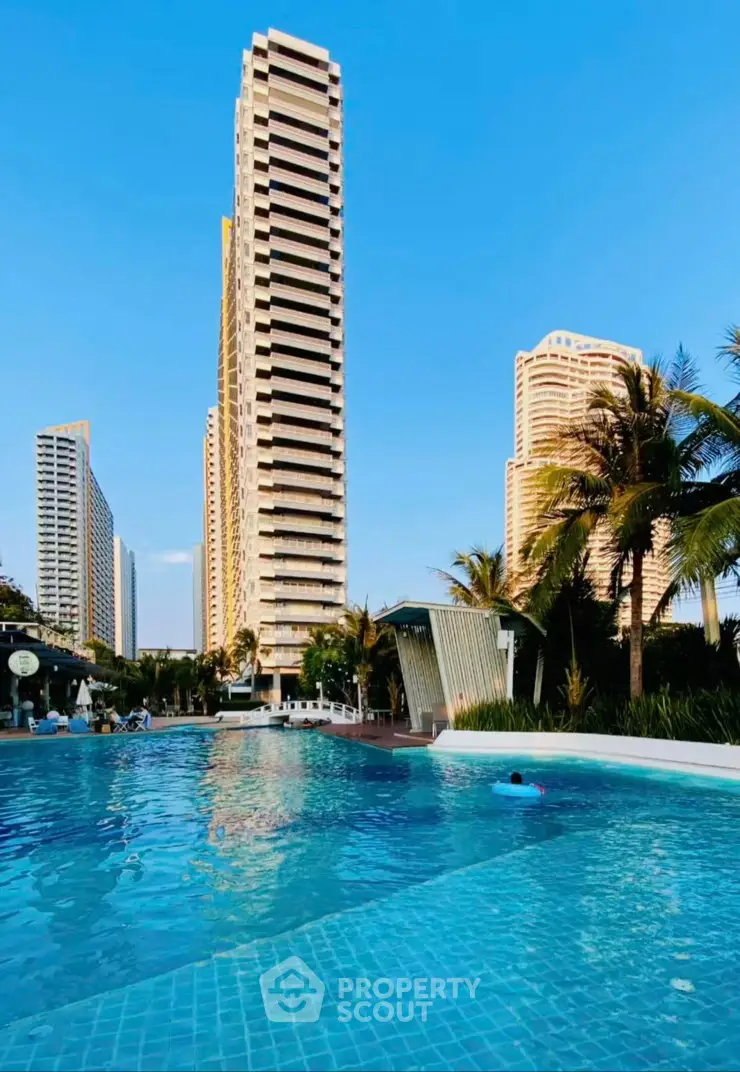 Luxurious high-rise condos with stunning pool and palm trees under clear blue sky.