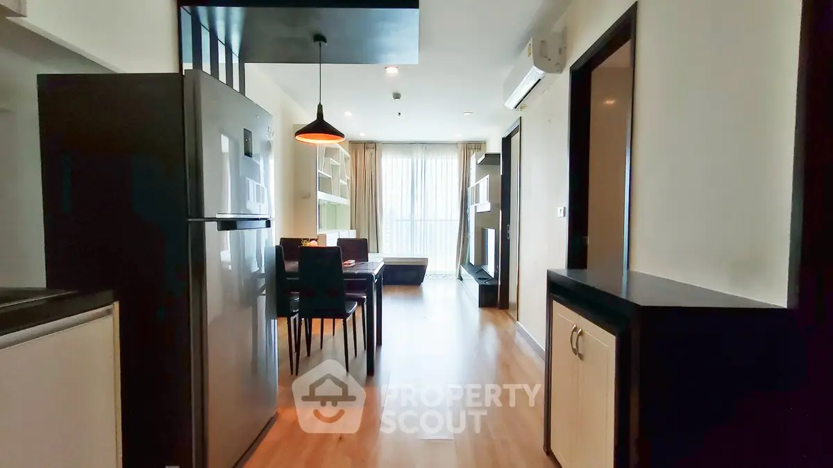 Modern apartment interior with open layout, featuring a sleek kitchen and cozy living area with natural light.