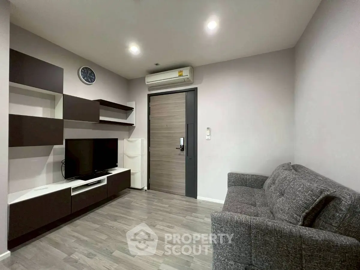 Modern living room with sleek furniture and wall-mounted TV in a cozy apartment.