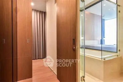 Modern bedroom with glass-enclosed bathtub and wooden sliding doors, offering a luxurious and stylish living space.