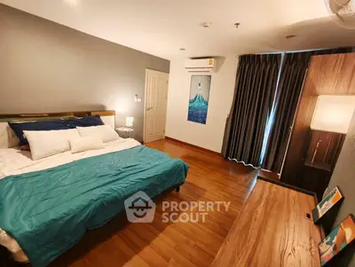 Spacious bedroom with wooden flooring and modern decor in a stylish apartment.