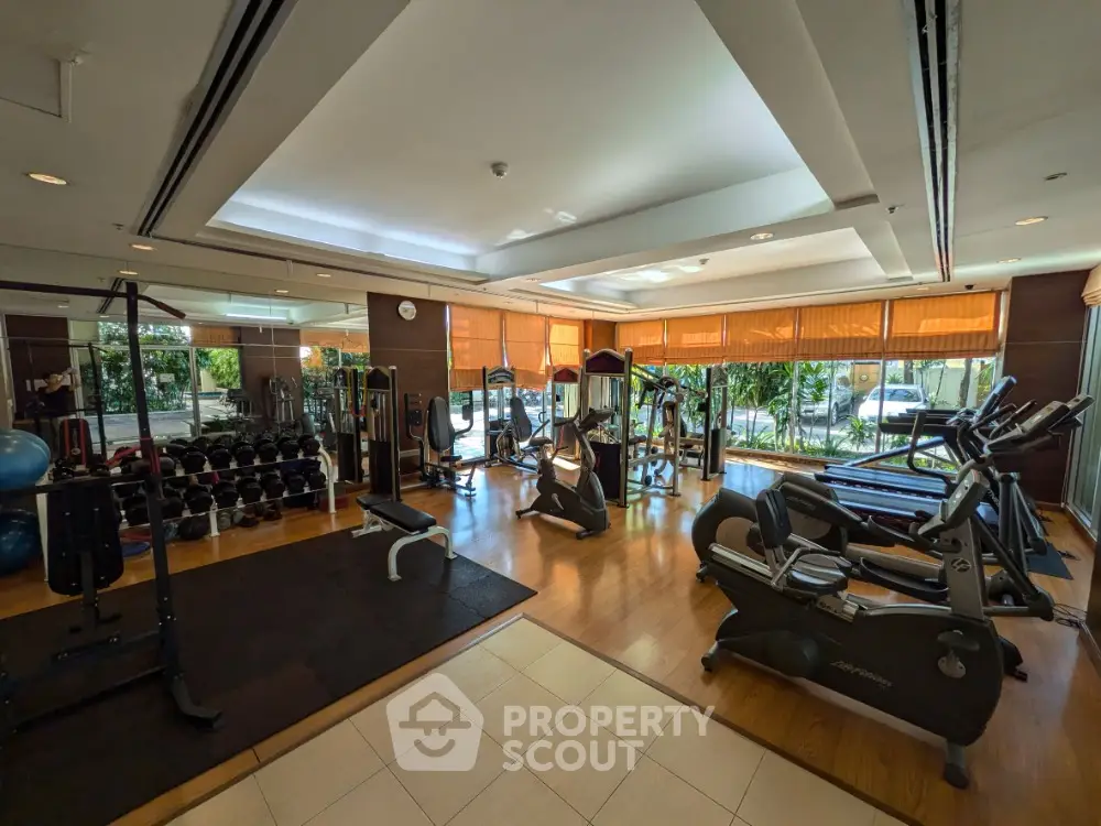 Spacious gym with modern equipment and natural lighting in luxury real estate property.
