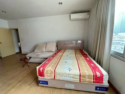 Spacious bedroom with modern decor and city view, featuring a cozy bed and stylish sofa.