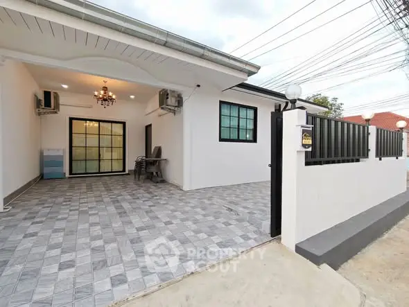 Modern single-story home with spacious tiled driveway and elegant exterior lighting.