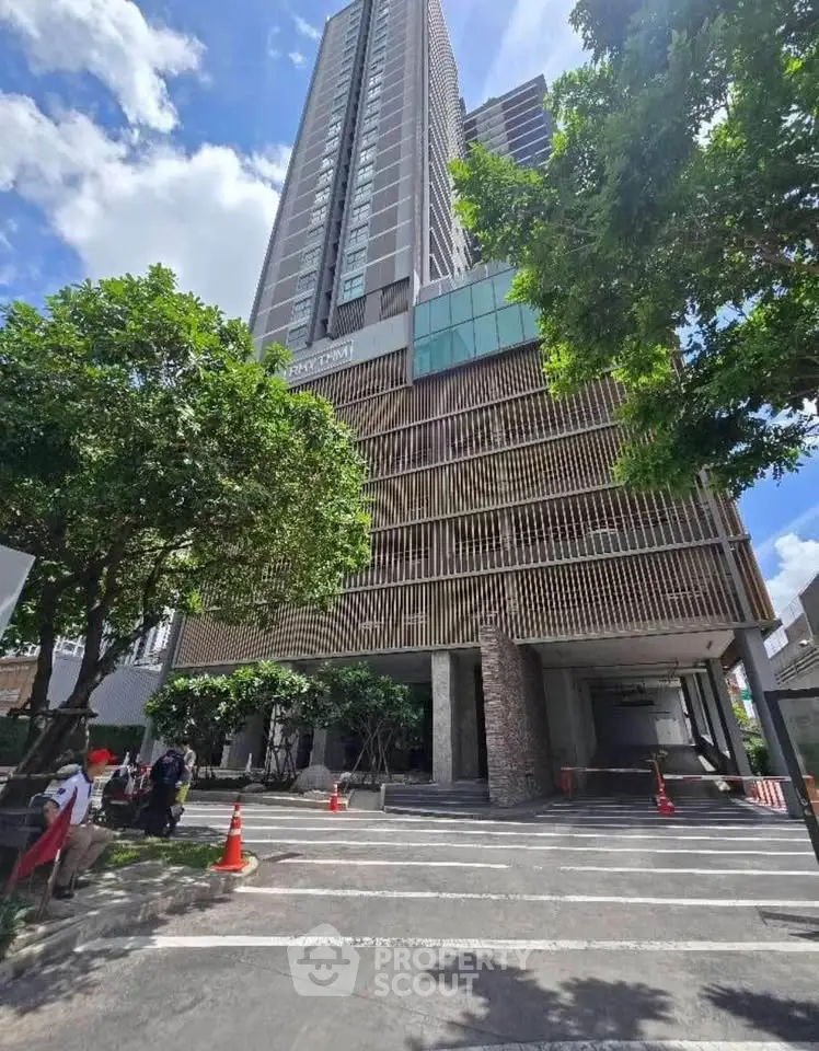 Modern high-rise building with lush greenery and spacious entrance, perfect for urban living.