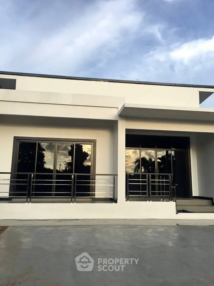 Modern minimalist white house exterior with large windows and sleek railing.