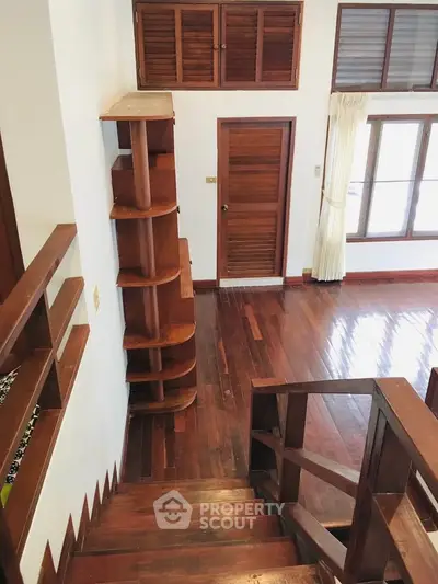 Spacious wooden interior with elegant staircase and natural light, perfect for modern living.
