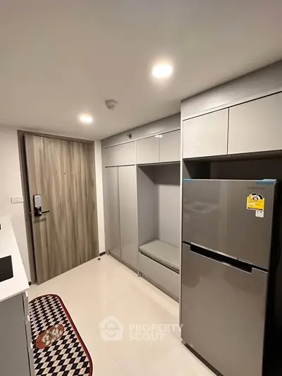 Modern kitchen with sleek cabinetry and stainless steel fridge in a compact layout.