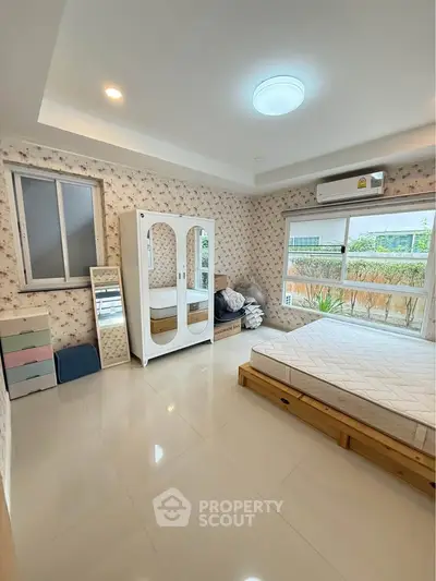 Spacious bedroom with large window and modern furnishings in a stylish home.