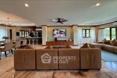 Spacious open-plan living room with elegant decor and modern kitchen, perfect for entertaining.