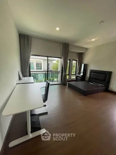 Spacious bedroom with modern furnishings and large windows offering natural light and garden view.