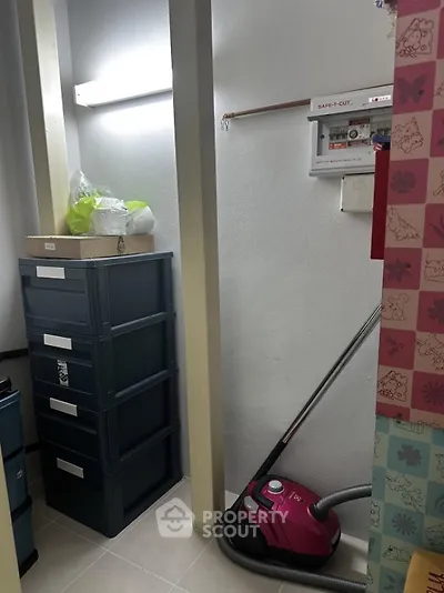 Compact storage room with vacuum cleaner and storage boxes, ideal for organizing household items.