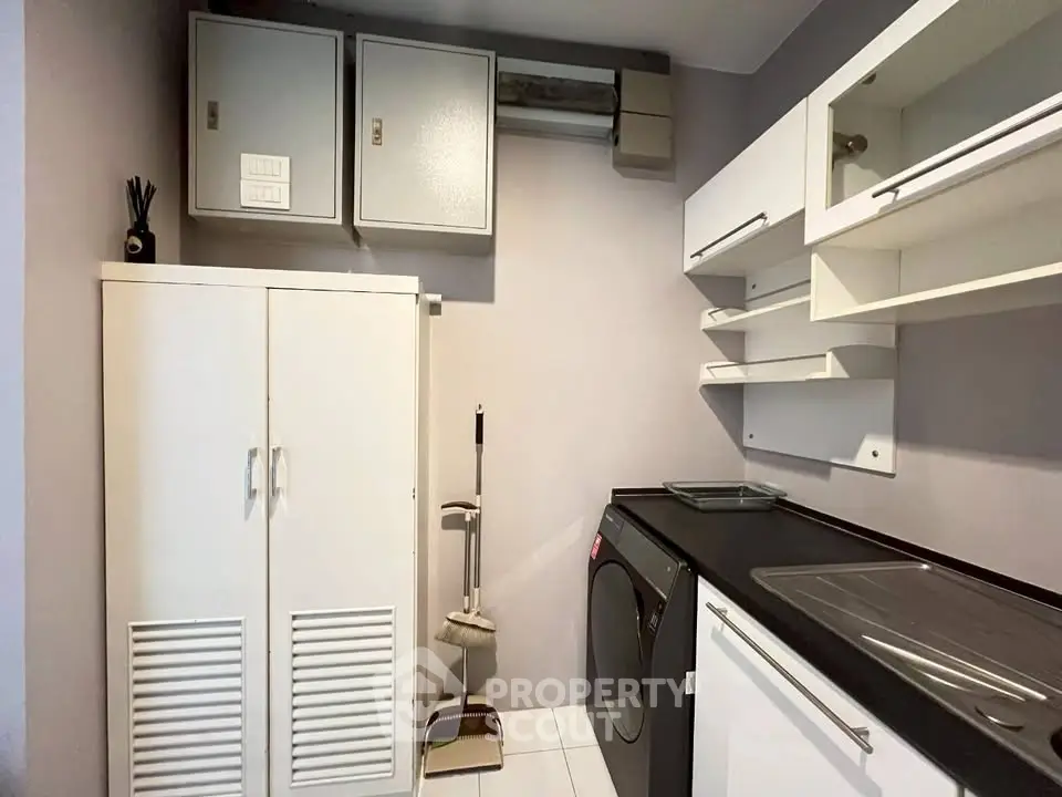 Modern laundry room with sleek cabinets and washing machine in stylish apartment.
