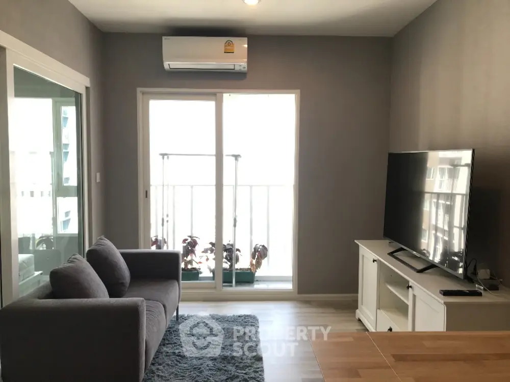 Modern living room with balcony, featuring sleek furniture and natural light.