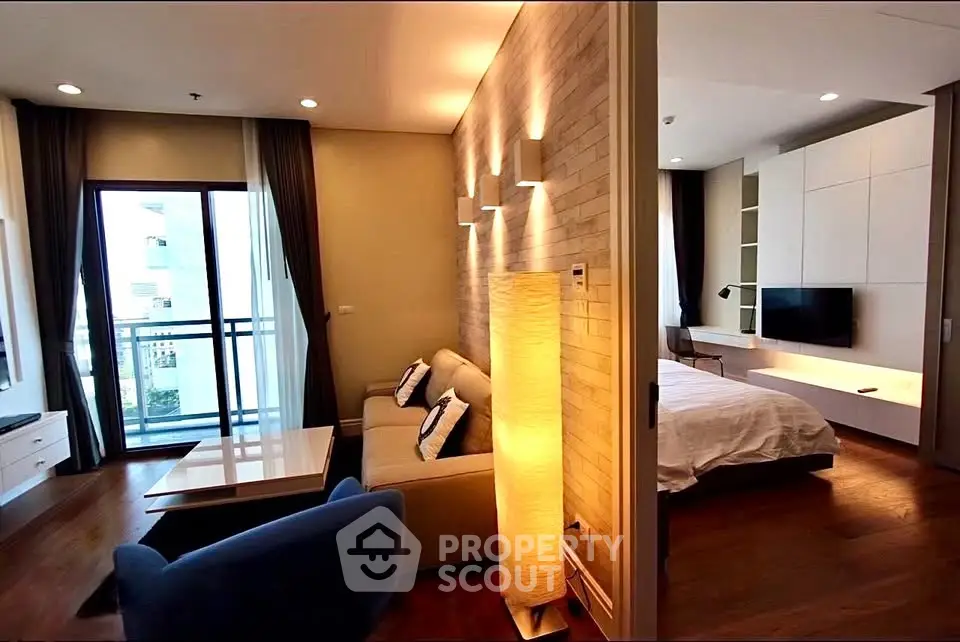 Modern living room with cozy lighting and adjacent bedroom, featuring a stylish open layout and balcony access.