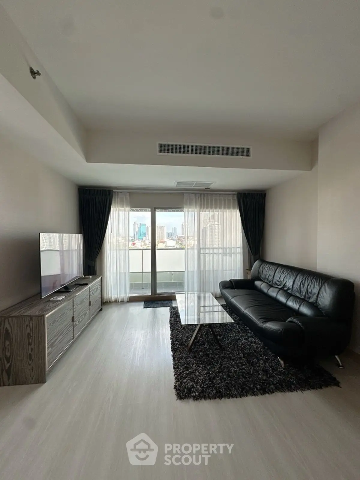 Modern living room with sleek black leather sofa and city view balcony