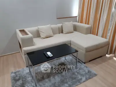 Modern living room with beige sectional sofa and sleek black coffee table on plush rug.