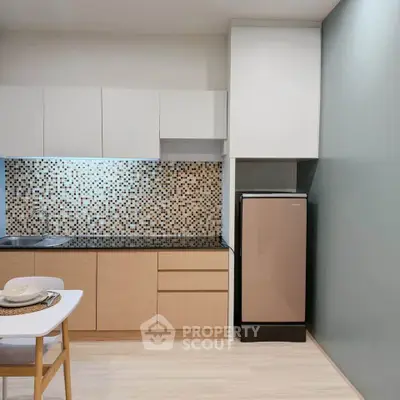 Modern kitchen with sleek cabinetry and stylish backsplash in a cozy apartment setting.